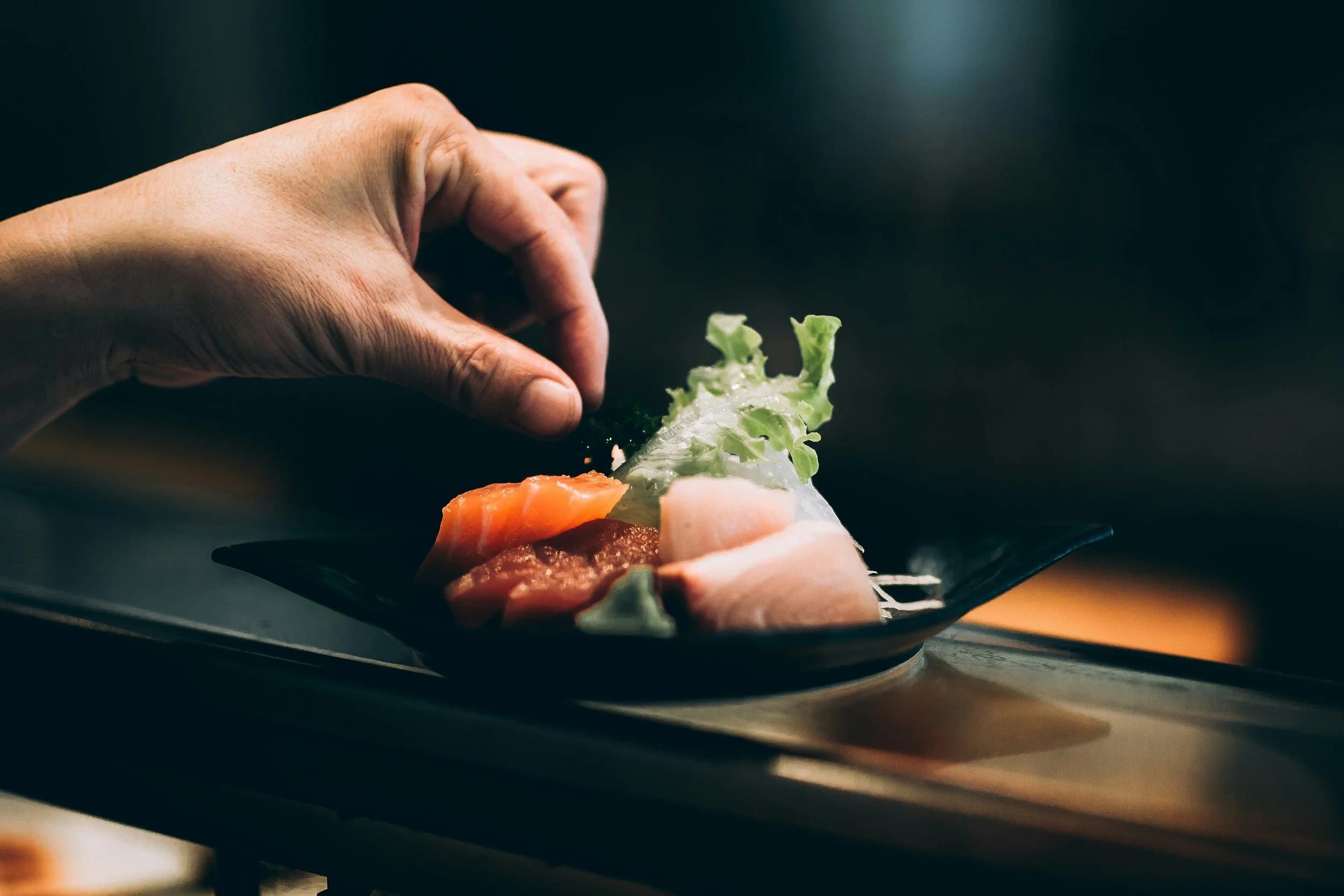 Close-up of a hand garnishing a plated dish.