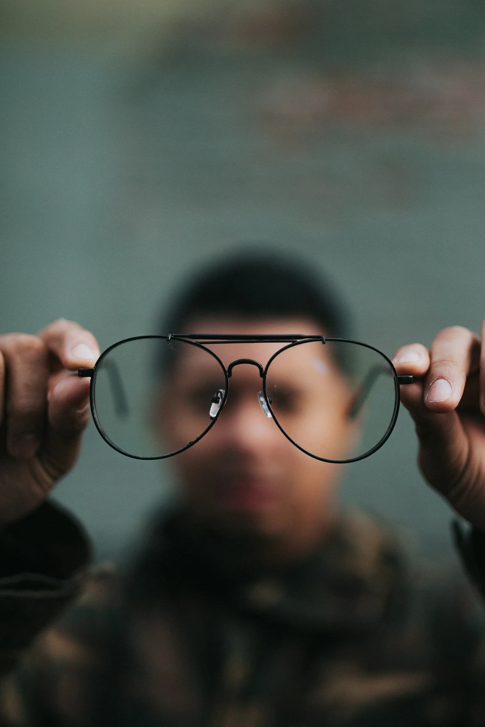 Person holding a pair of sunglasses.