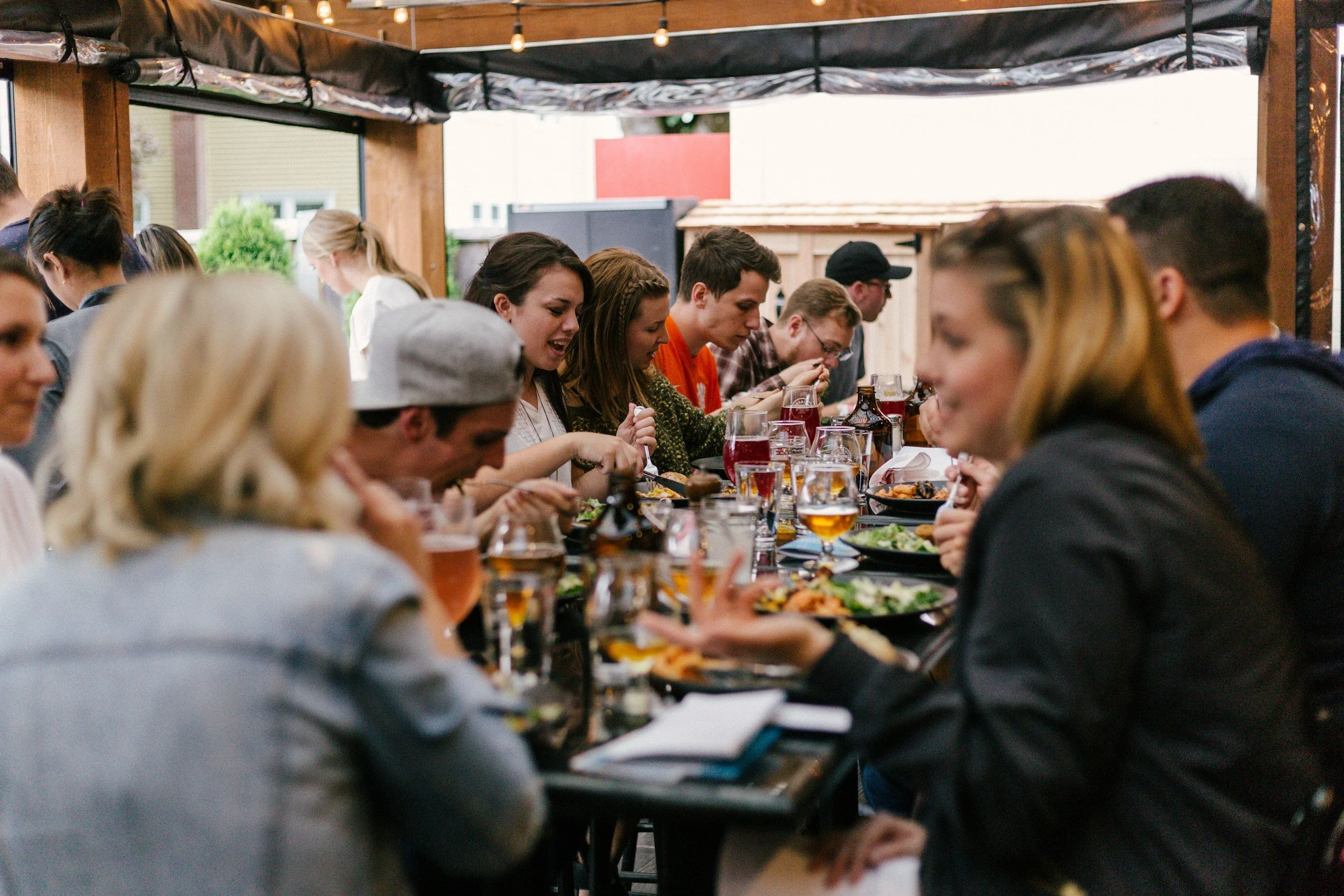 A full table of people enjoying a meal at a restaurant on a patio